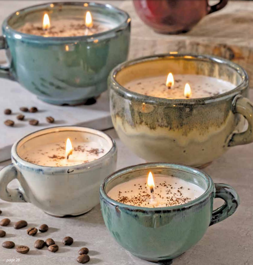 Four Small Coffee Cup Swan Creek Candles with lit pure soy candles and coffee beans sprinkled around on a table.