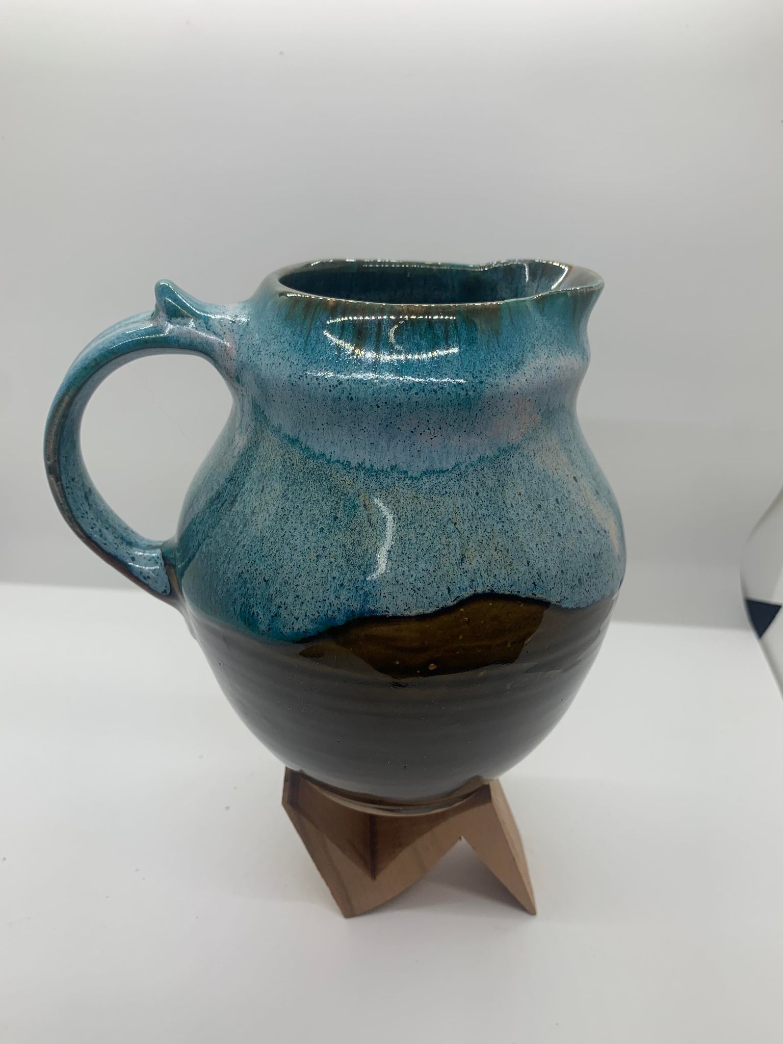 A Perry Munn Pottery Small Pitcher on a wooden stand