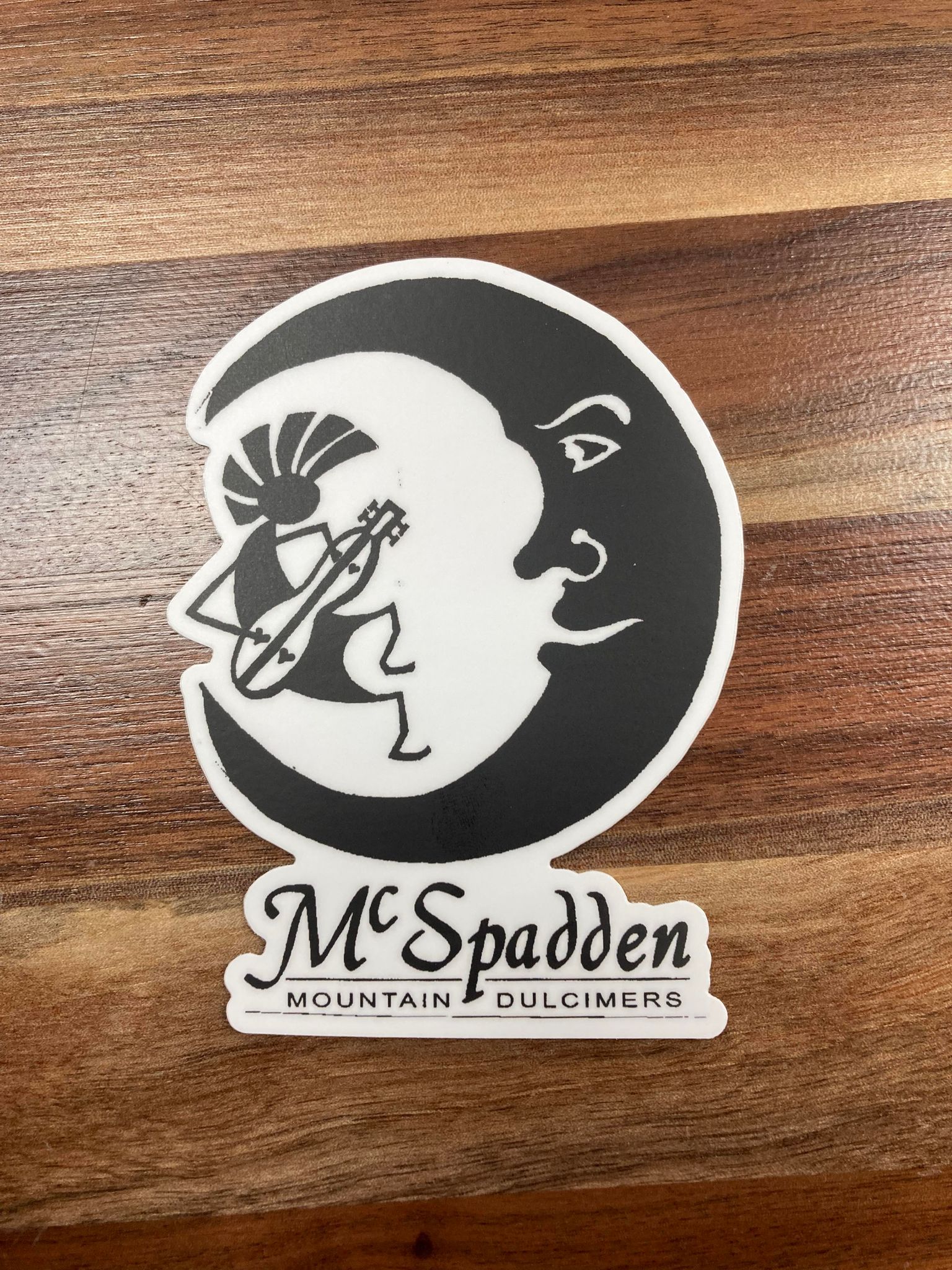 McSpadden Stickers for decorating laptops, featuring a logo with stylized imagery of a moon and a person playing a stringed instrument, with the text "mcspadden mountain dulcimers" displayed below.