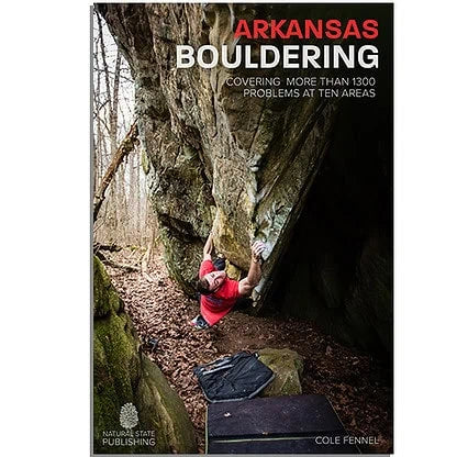 Book cover of "Arkansas Bouldering" depicting a climber in red shirt scaling a large, mossy rock with bouldering mats beneath, solving a complex boulder problem.
