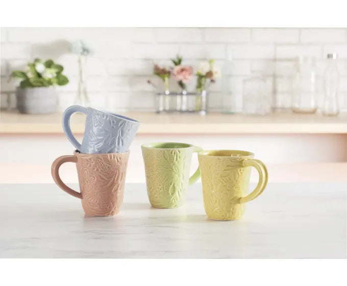 A vibrant display of Studio M Coffee Mugs from the Heart Notes collection graces the counter.