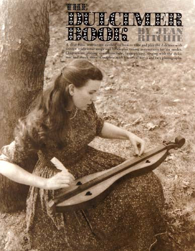 A young woman in vintage clothing plays traditional songs from The Dulcimer Book by Jean Ritchie outdoors, seated beside a tree in a wooded area.