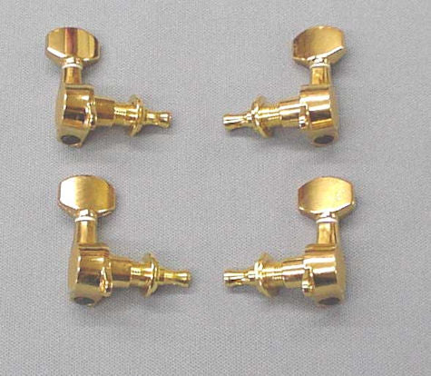 Four Gold Plated Tuning Pegs on a flat gray surface.