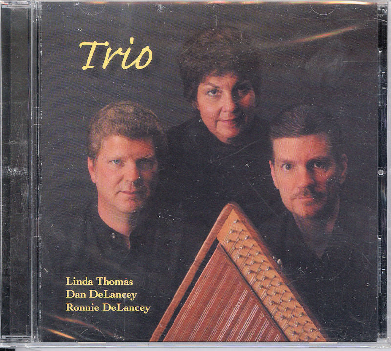 CD album cover featuring the product Trio - by Linda Thomas, Dan and Ronnie Delancey featuring a musical trio, two men and one woman, with instruments including a hammered dulcimer. Text reads "Trio, Linda Thomas, Dan and Ronnie DeLancey.