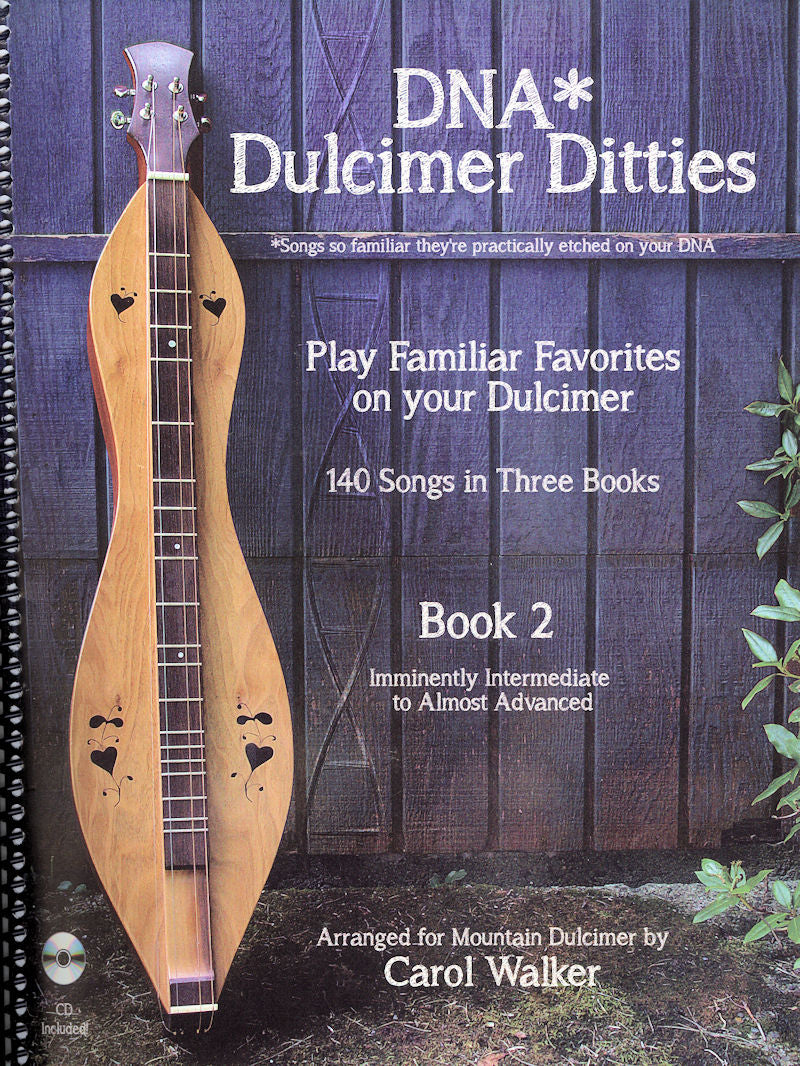 A dulcimer in Dadd tuning leaning against a wooden background with a book titled "DNA* Dulcimer Ditties, Book 2 - Carol Walker", featuring