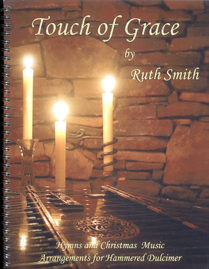 A spiral-bound book titled "Touch Of Grace by Ruth Smith" with an image of three candles on a piano, reflecting light on stone walls.