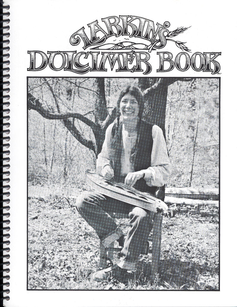 Cover of "Larkin's Dulcimer Book" featuring a grayscale photo of a smiling woman sitting on a rock in a wooded area, holding a dulcimer instruction book.