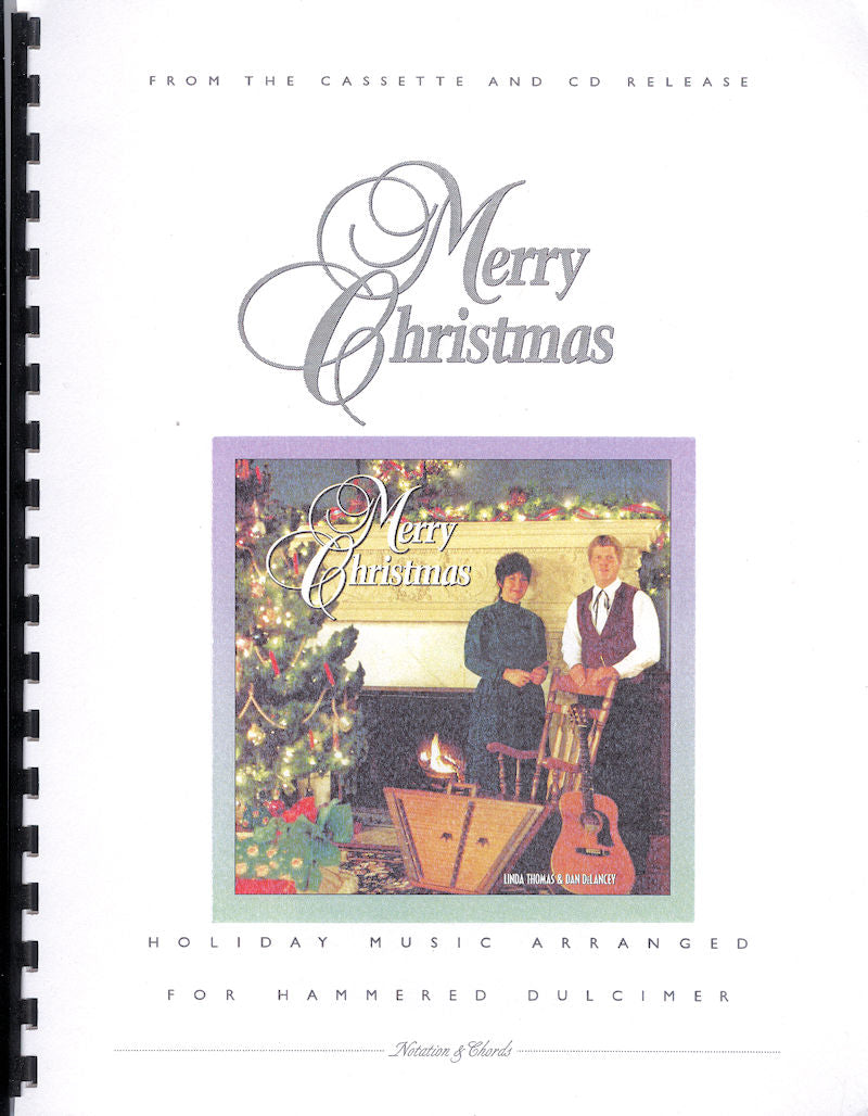 Cover of "Merry Christmas by Linda Thomas" book featuring two musicians by a Christmas tree, text announcing a cassette and CD release, and a mention of music for hammered dulcimer.