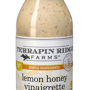 A bottle of Terrapin Ridge Lemon Honey Vinaigrette with a white label, black and yellow text, and visible herbs in the dressing.