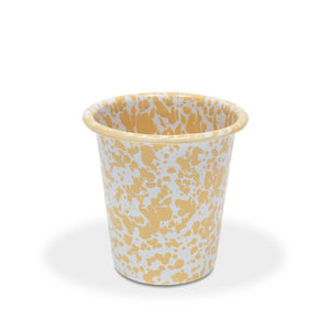 The Splatter Enamelware 10 oz Short Tumbler is a small white cup adorned with a cheerful yellow splatter pattern, reminiscent of festive party colors and designs, set against a plain white background.