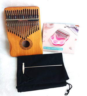 A Kalimba Musical Instrument with metal tines alongside its instruction manual, tuning hammer, and carrying pouch, displayed on a white background.