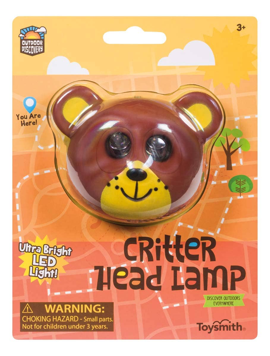 A Outdoor Discovery Critter Head Lamp toy packaging, featuring a cartoon bear with LED light eyes and an adjustable elastic headband, labeled for ages 3+ against an illustrated outdoor backdrop.