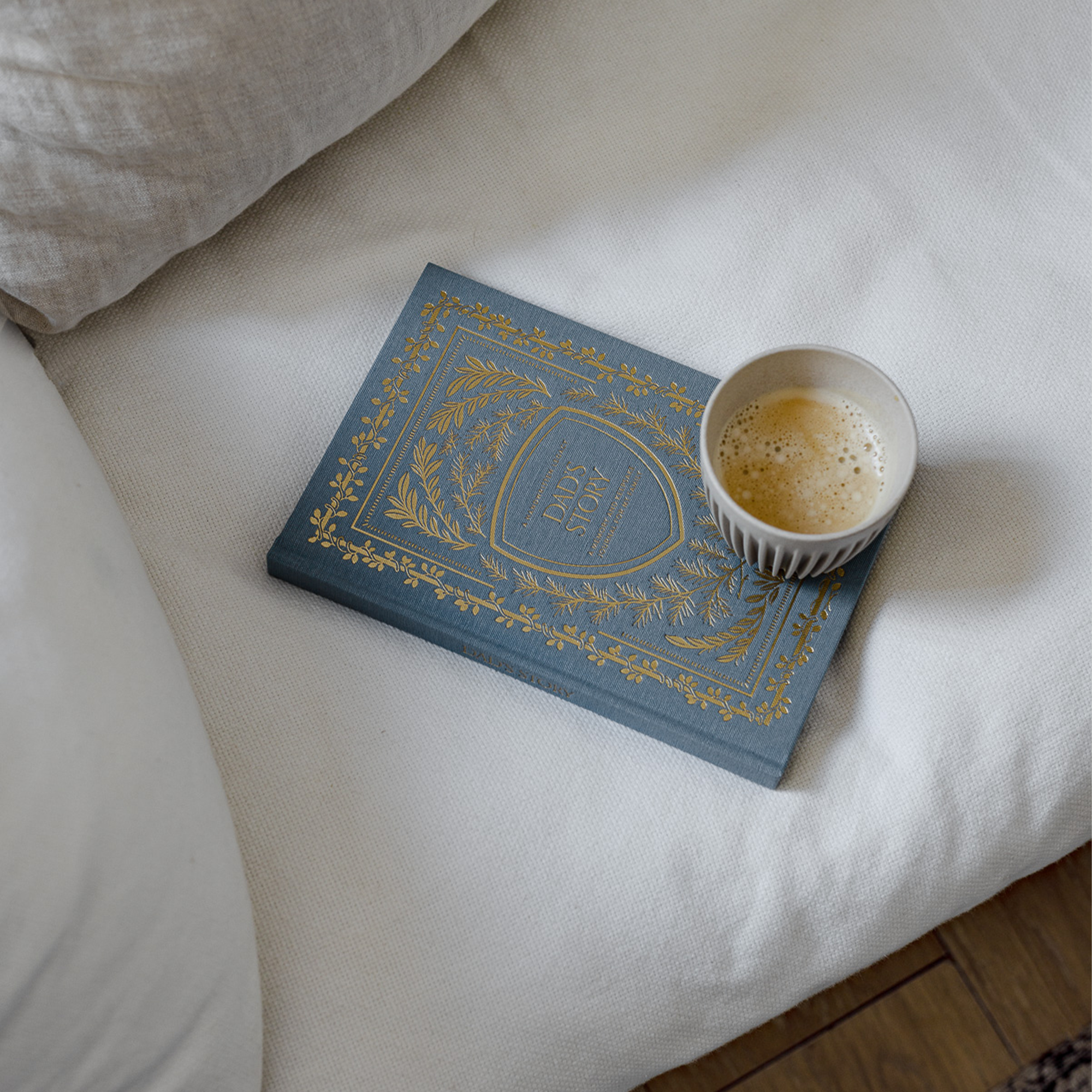 A Dad's Story memory book on a bed with a cup of coffee.