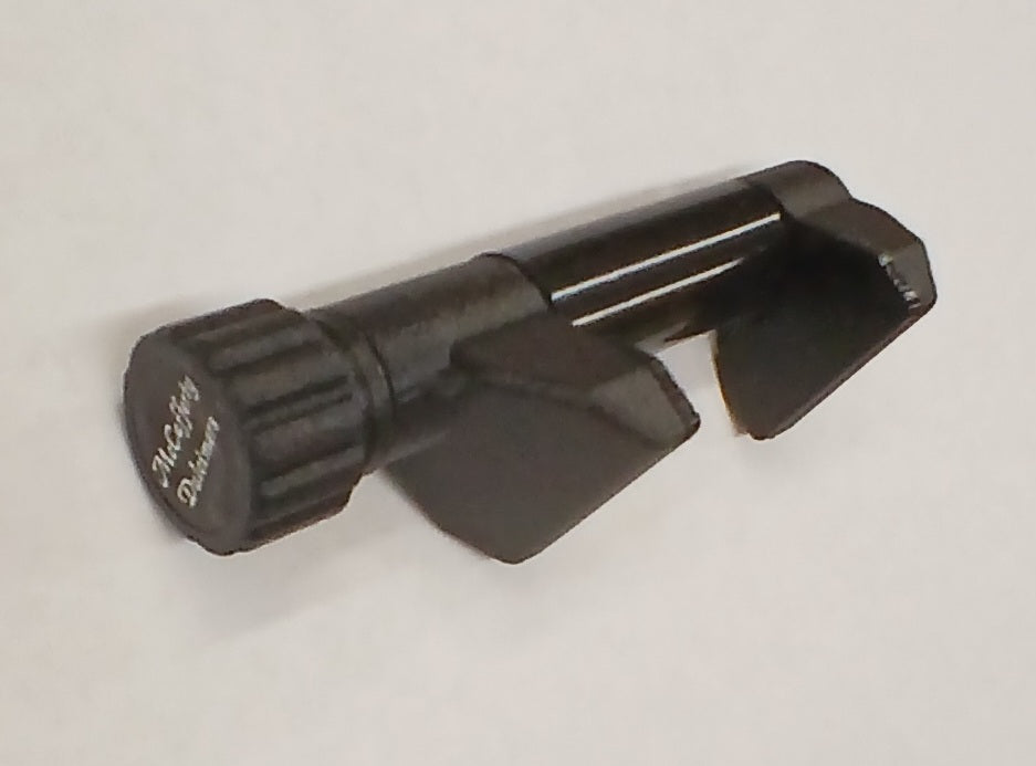 The McCafferty Capo is a black plastic tool with a cylindrical body, two angled prongs, and a ridged knob labeled "McGuffy Devices," designed for six-string dulcimer use and shown on a white surface.
