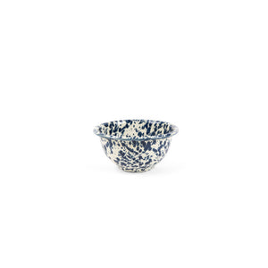The Splatter Enamelware Small Footed Bowl features a striking blue and white speckled pattern inspired by classic enamelware designs, and is showcased against a clean white background. Holding 16 oz, this bowl is ideally sized for serving dips while blending timeless style with everyday functionality.
