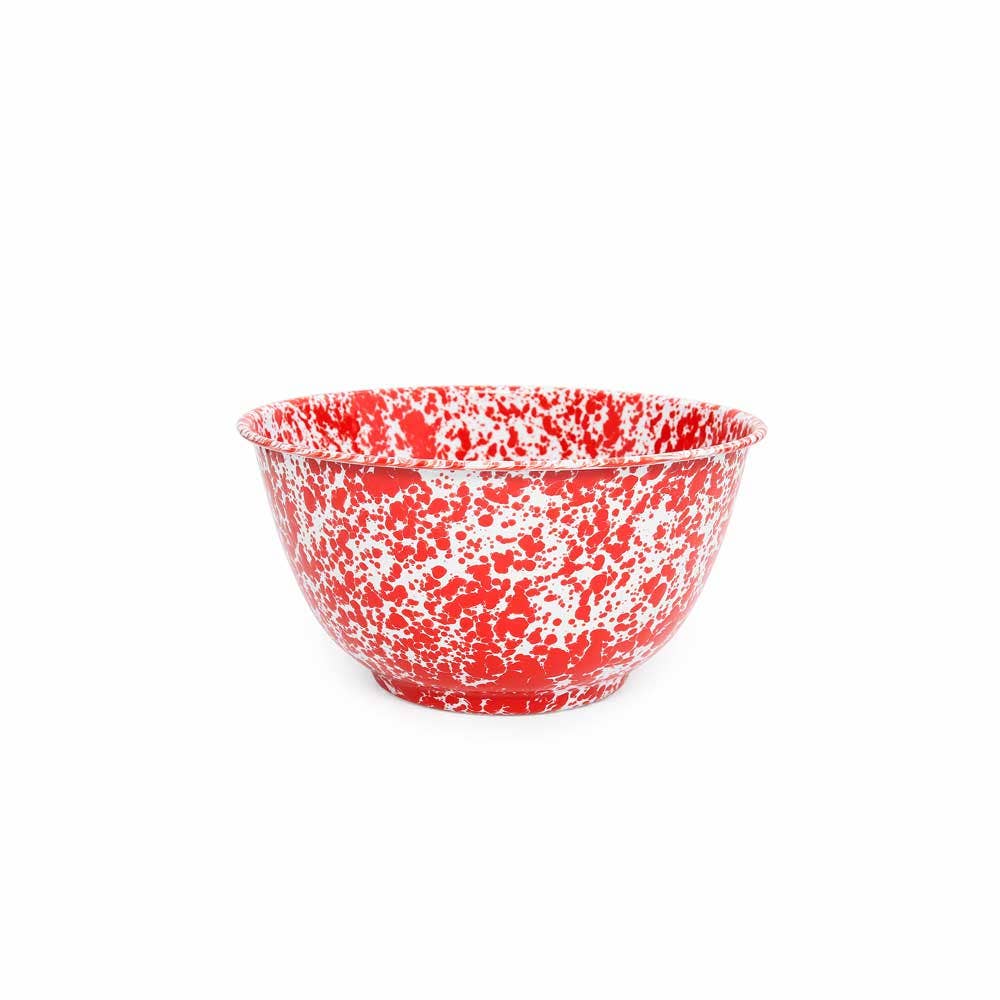 The Splatter Enamelware Large Salad Bowl, featuring a red and white speckled design, round shape, and flared lip, is set against a plain white background. This durable piece is also highly versatile.