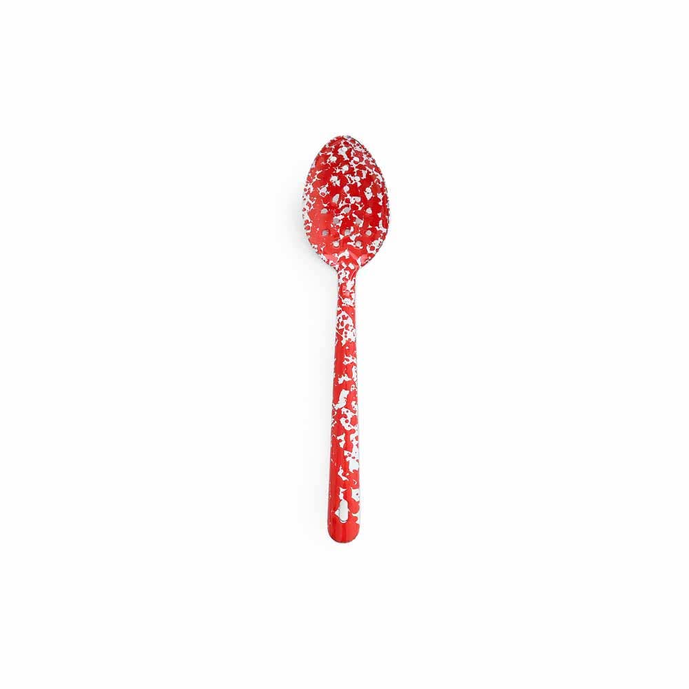 A large slotted spoon from the Splatter Enamelware collection, featuring a vibrant red hue with white speckled patterns, set against a plain white background.