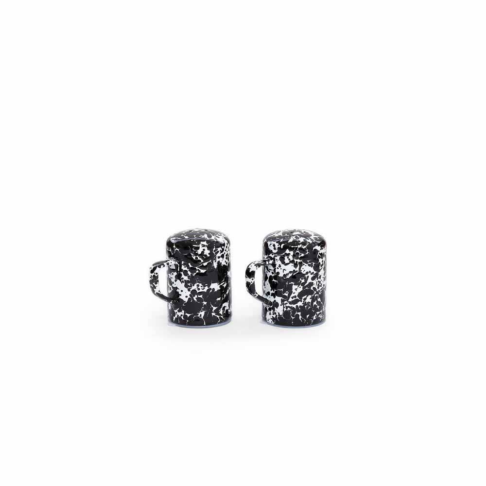 Two items from the Splatter Enamelware Salt & Pepper Shaker Set, featuring a black and white marbled design with handles and each holding up to 11 oz, are placed side by side against a plain white background.