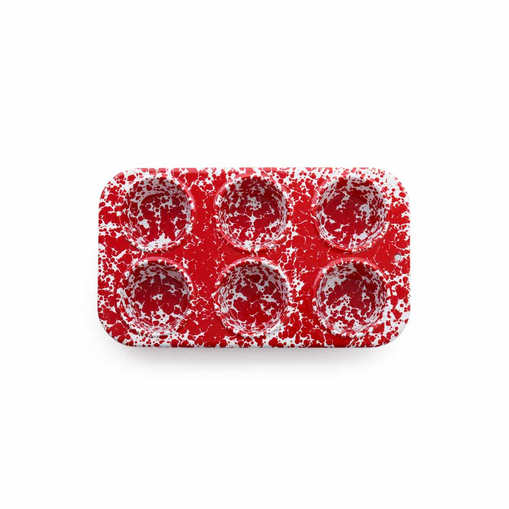 The Splatter Enamelware 6-cup Muffin Tin, featuring a durable red and white speckled design and viewed from above, promises both style and ease of cleaning.