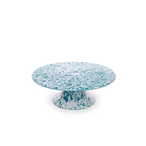 The Splatter Enamelware Cake Stand, with its round shape and blue-and-white speckled design reminiscent of classic enamelware, stands against a plain white background. Perfect for entertaining, its colorful design adds a touch of charm to any setting.