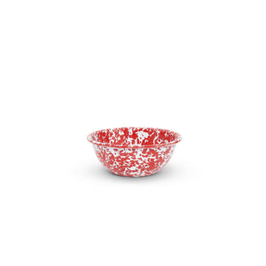 A small, round Splatter Enamelware 20 oz Cereal Bowl with a red and white speckled pattern sits on a white surface, centered in the image. This piece of vibrant enamelware is perfect for entertaining a crowd.