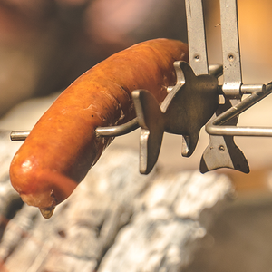 A sausage is being roasted over an open flame using the Fire Fishing Pole.