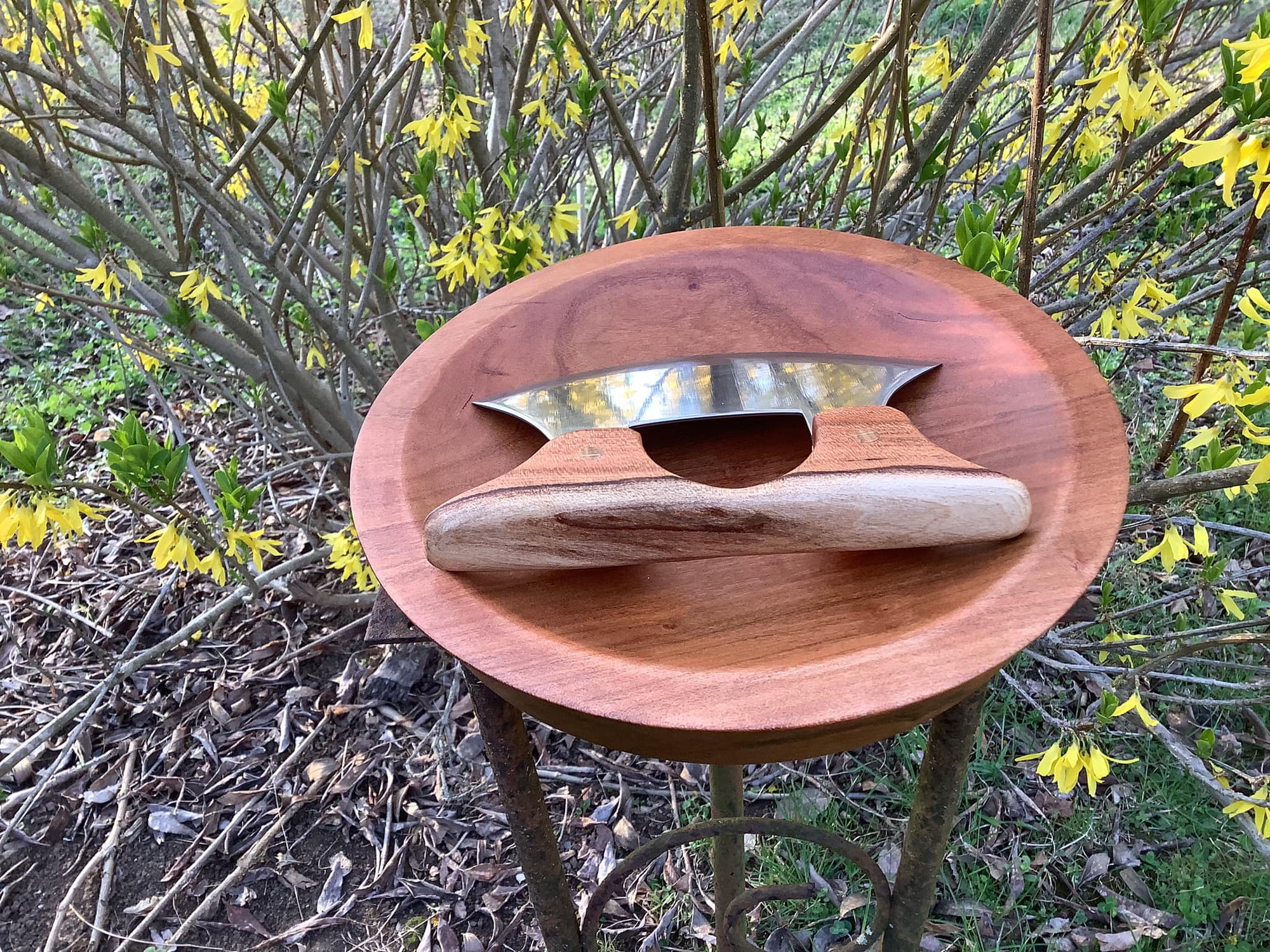 An exquisite Ulu Bowl and Knife with Handmade Handle sits on top of a flower pot, showcasing both functionality and elegance.