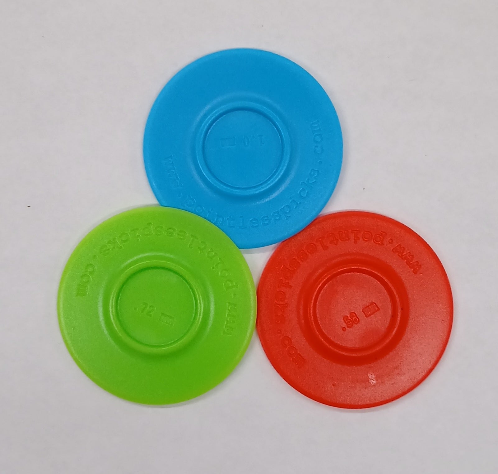 Three Pointless Pick plastic disks in blue, green, and red, with measurements (.10, .72, .08) and a website URL are displayed on a white surface.