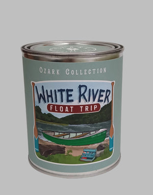 The Scented Palette Candle Float Trip is a metal can from the Ozark Collection labeled "White River Float Trip," featuring a river with paddles, trees, and a parked vehicle. Perfect for reuse as a candle tin, it offers a refreshing floral citrus scent.