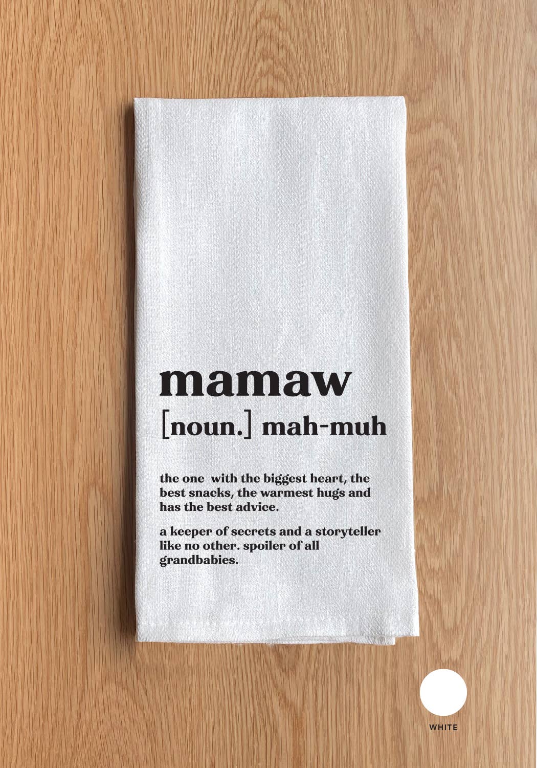 A Mamaw definition White Kitchen Towel rests on a wooden surface, displaying the sentiment "the one with the biggest heart, the best snacks, the warmest hugs, and the best advice" in black text.