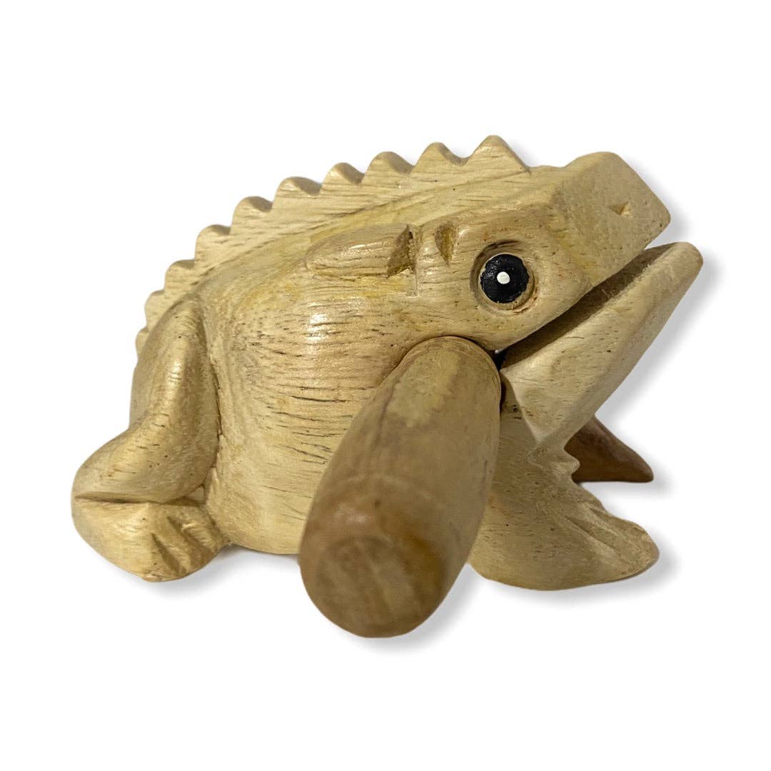 The Natural wooden frog is a small, lightweight sculpture made from wood, featuring a simplistic design with a mouth and black eyes. A wooden stick is positioned under its chin for added detail. Handmade in Thailand, this piece exemplifies quality craftsmanship.