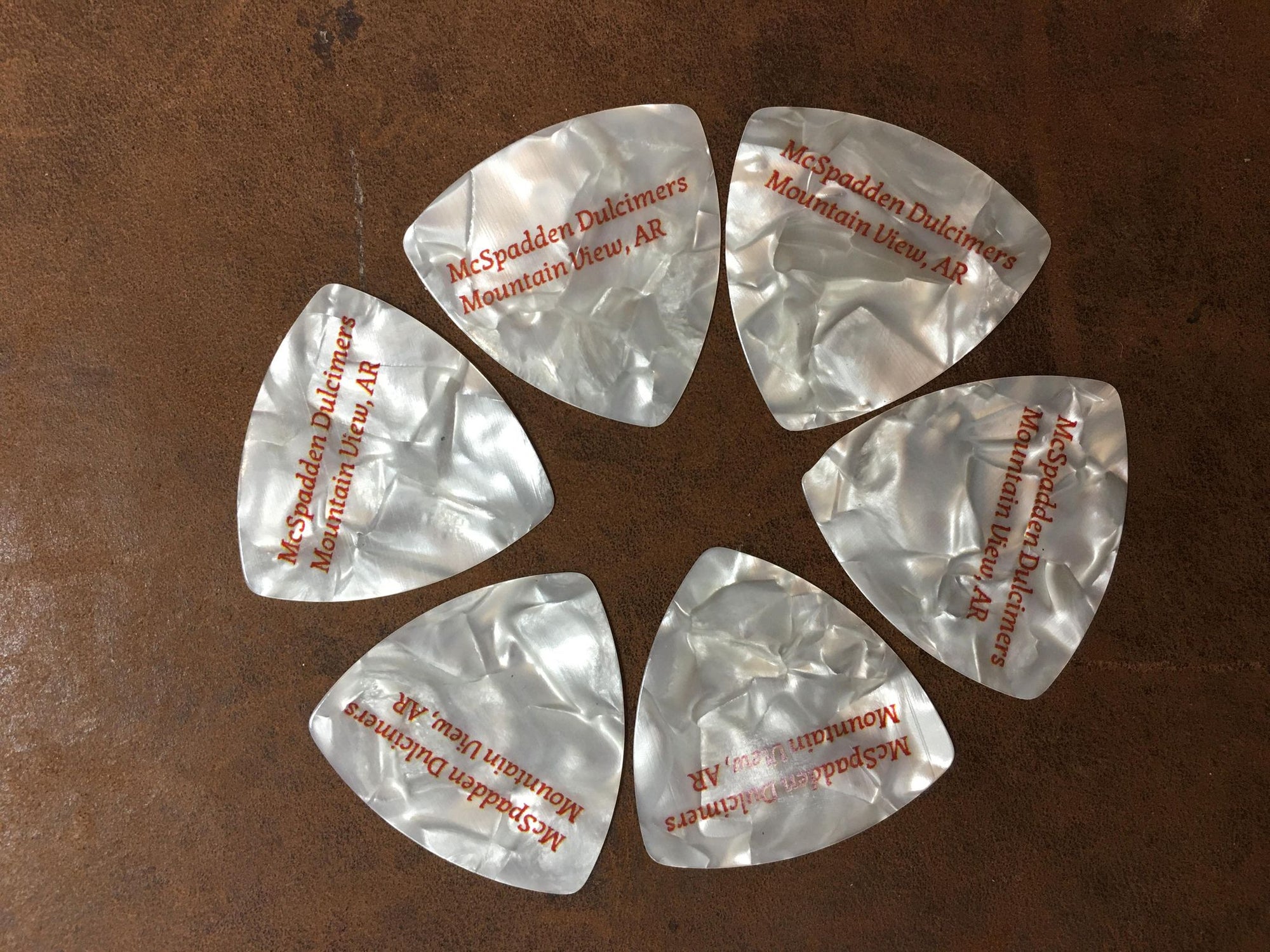 Five McSpadden Picks - Set of 6 guitar picks are arranged in a circle on a table.