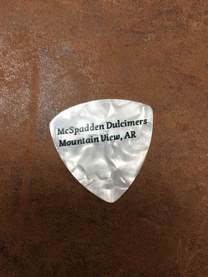 A white pearloid thin triangle guitar pick with the words "McSpadden Picks" engraved on it.