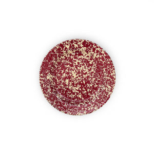 The Splatter Enamelware Flat Salad Plate features a round shape with a cream background and red splatter pattern, offering durability and versatility for everyday use.