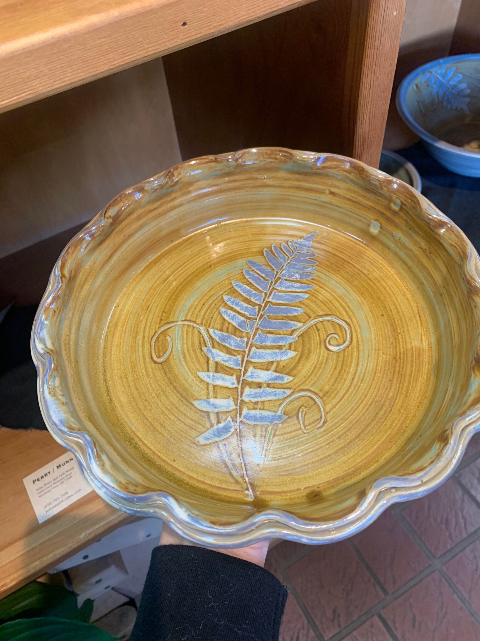 A person is holding a Perry Munn Pottery Fern Pie Plate.