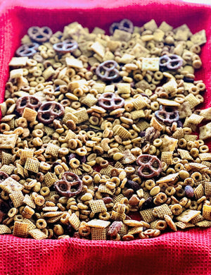 A blend of cereal, pretzels, and nuts delicately seasoned with Snickerdoodle Cracker Seasoning, all elegantly laid out on a red cloth.