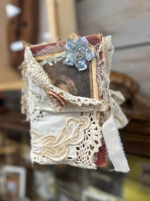 A small Mrs. Pat's Junk Journal created by a local artist hangs on a shelf.