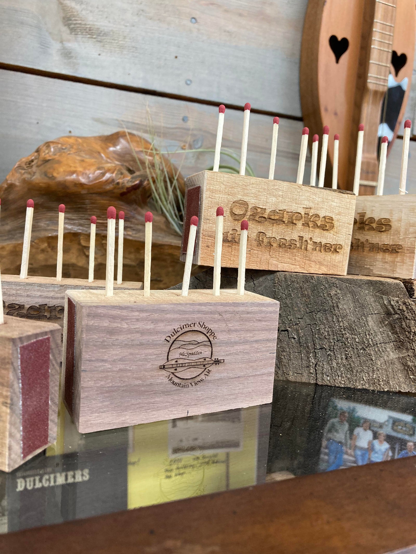 A collection of Ozark Air Fresh'ner stands for dulcimers, crafted in the Ozarks, displayed on a shelf.