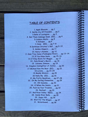 Spiral-bound book open to a Table of Contents page, listing song titles and corresponding page numbers. The title at the top reads "TABLE OF CONTENTS," with Red Dog Jam highlighted as a key track in this 30 Tunes for the Banjo/Dulcimer, also featuring an accompanying CD for practice sessions.