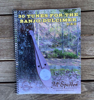 Cover of a spiral-bound book titled "30 Tunes for the Banjo/Dulcimer" by McSpadden Mountain Dulcimers, featuring an image of a dulcimer leaning against a tree. This guitar tab book includes a special section on Red Dog Jam.
