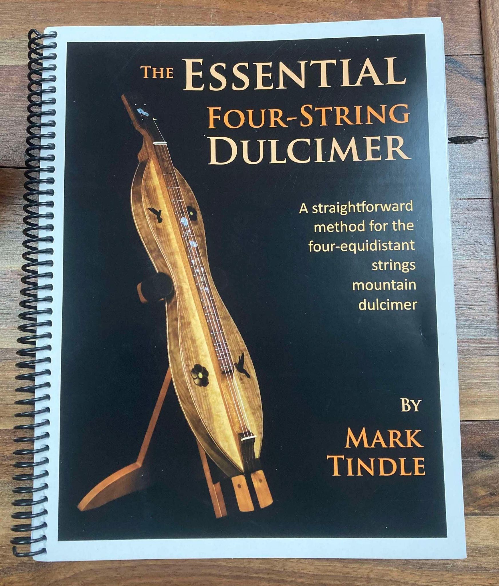 Cover of The Essential Four String Dulcimer by Mark Tindle, featuring a dulcimer on a stand and a text blurb about teaching methods for four-equidistant strings mountain dulcimer with D-A-D-D tuning.