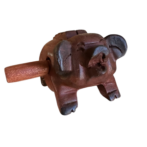 Wooden Musical Pig Percussion Instrument featuring a cylindrical handle through its side, with carved ears, eyes, and legs, shown against a white background.