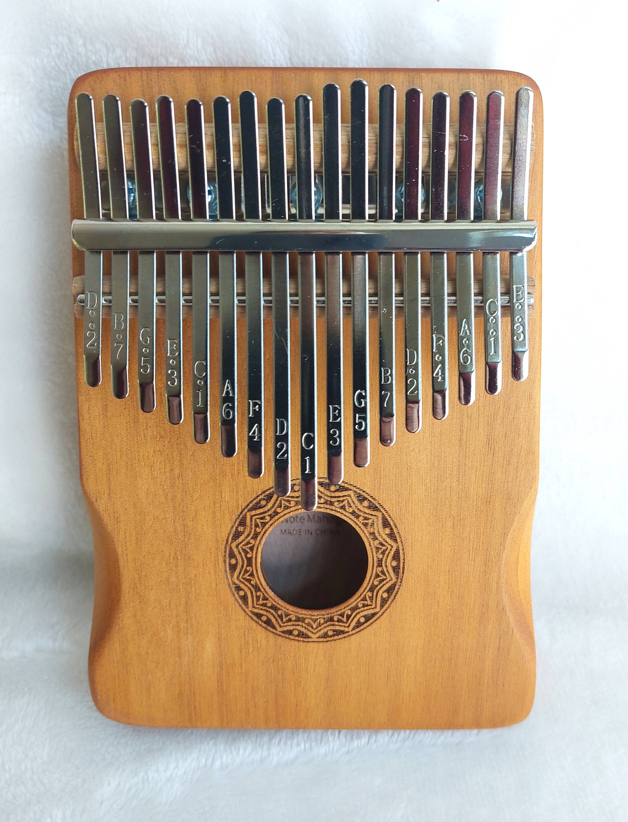 A Kalimba Musical Instrument, a musical instrument with metal tines labeled with notes, set on a wooden body with a central sound hole.
