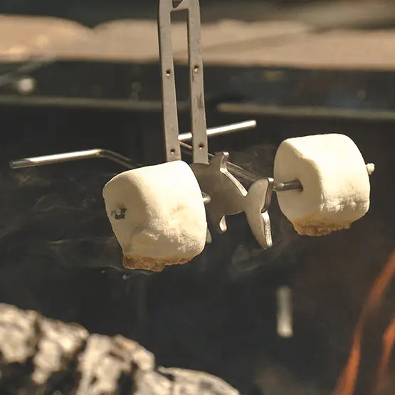 Two marshmallows roasting on a Fishing Poles roaster over a campfire.