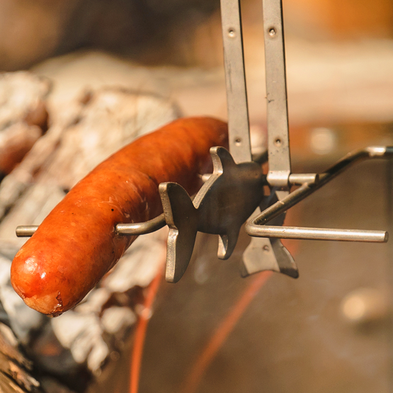 A Combo Display - Corrugated cooks over a campfire, held by an animal roasters fork with a wooden handle.