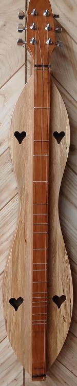 A handcrafted 6-string, hourglass dulcimer with heart-shaped sound holes, cherry back and sides, and a spalted top sits elegantly on a wooden surface. Resembling a dulcimer akin to McSpadden Dulcimers, it promises unmatched quality and includes a lifetime warranty.