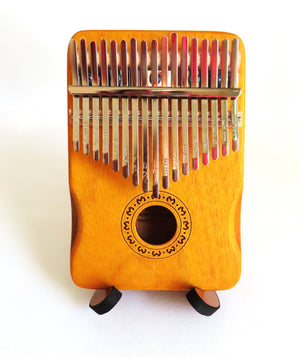 A wood kalimba with metal tines arranged in two rows is elegantly showcased on a solid Kalimba Stand - Wood against a white background.