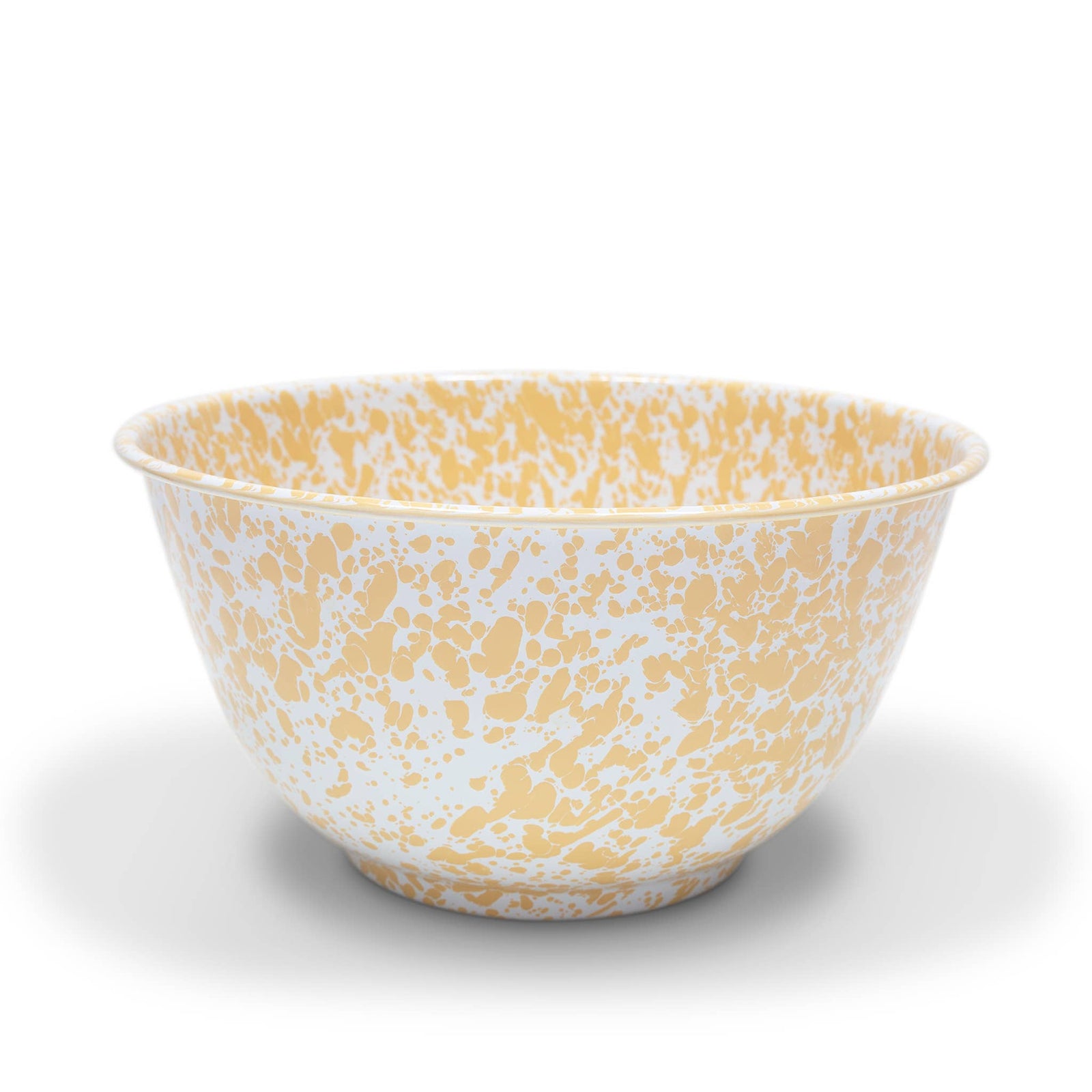 The Splatter Enamelware Large Salad Bowl, featuring a versatile white ceramic base with a yellow splatter pattern, sits on a plain white surface, showcasing its durable design.