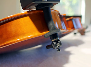 Close-up of a violin body on a white surface, featuring the instrument’s endpin with a Myers Quick Mount Petite 6" Pickup - External attached.