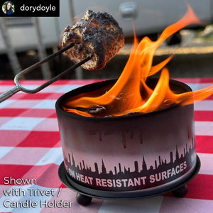 A marshmallow on a stick being roasted over a Mini Portable Fire Pit (City Bonfires® by Coleman®), with the base labeled "shown with trivet / candle holder.